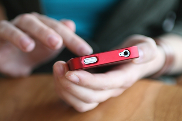 Young Woman's Hands Holding Red Smart Phone